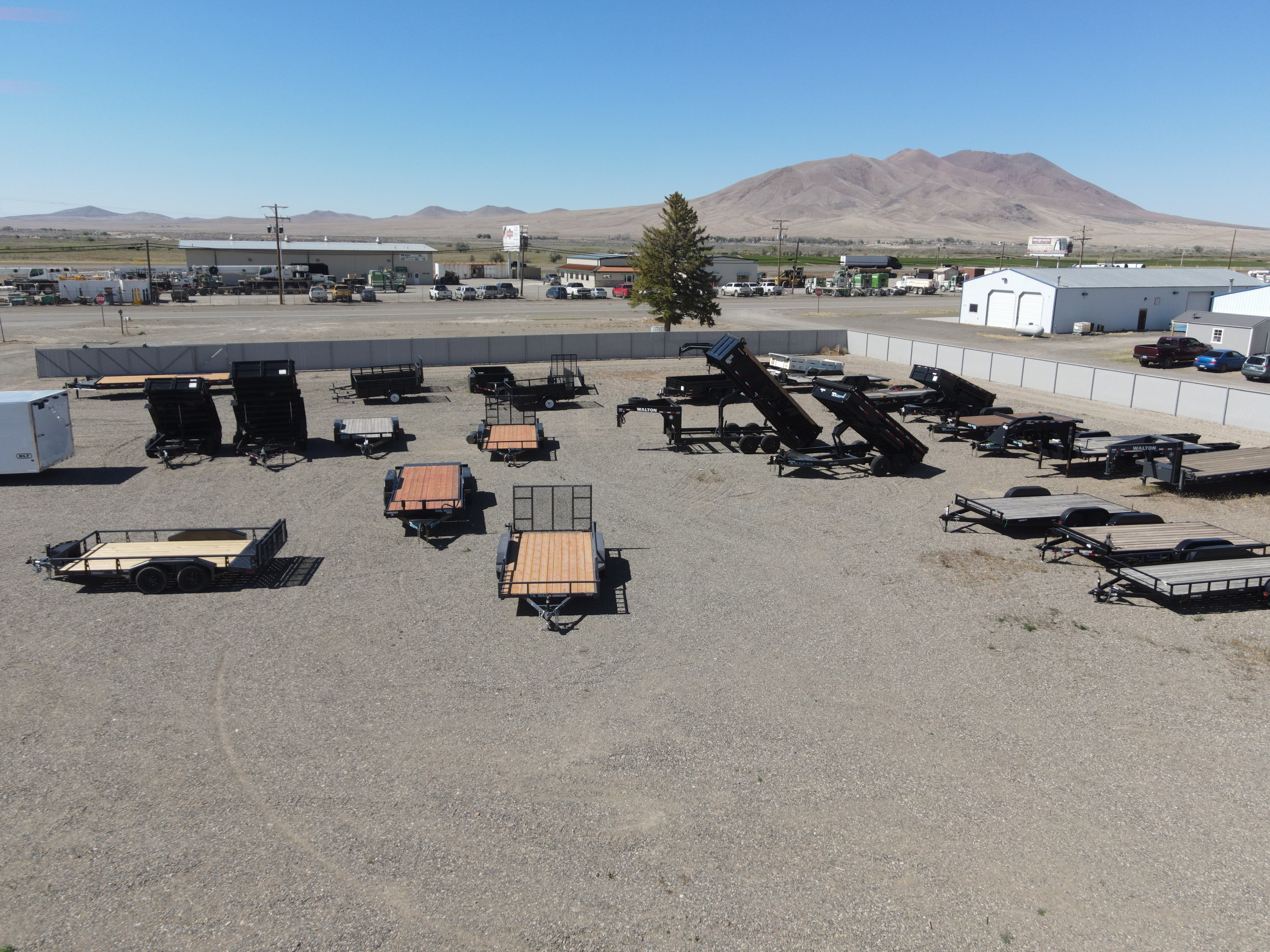 Aerial view of The Trailer Store lot in Winnemucca, Nevada — dumps, utilities, and flatbeds on the yard with mountains beyond